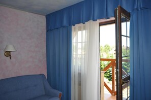 Una habitación con un sofá azul, una lámpara de pared y una ventana con cortinas azules.