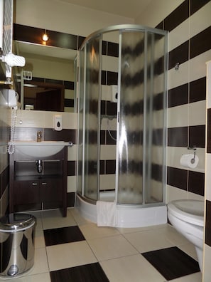 A bathroom with a glass-enclosed shower, a sink with a mirror, and a toilet.