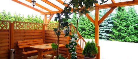 A wooden pergola with a bench and potted plants.
