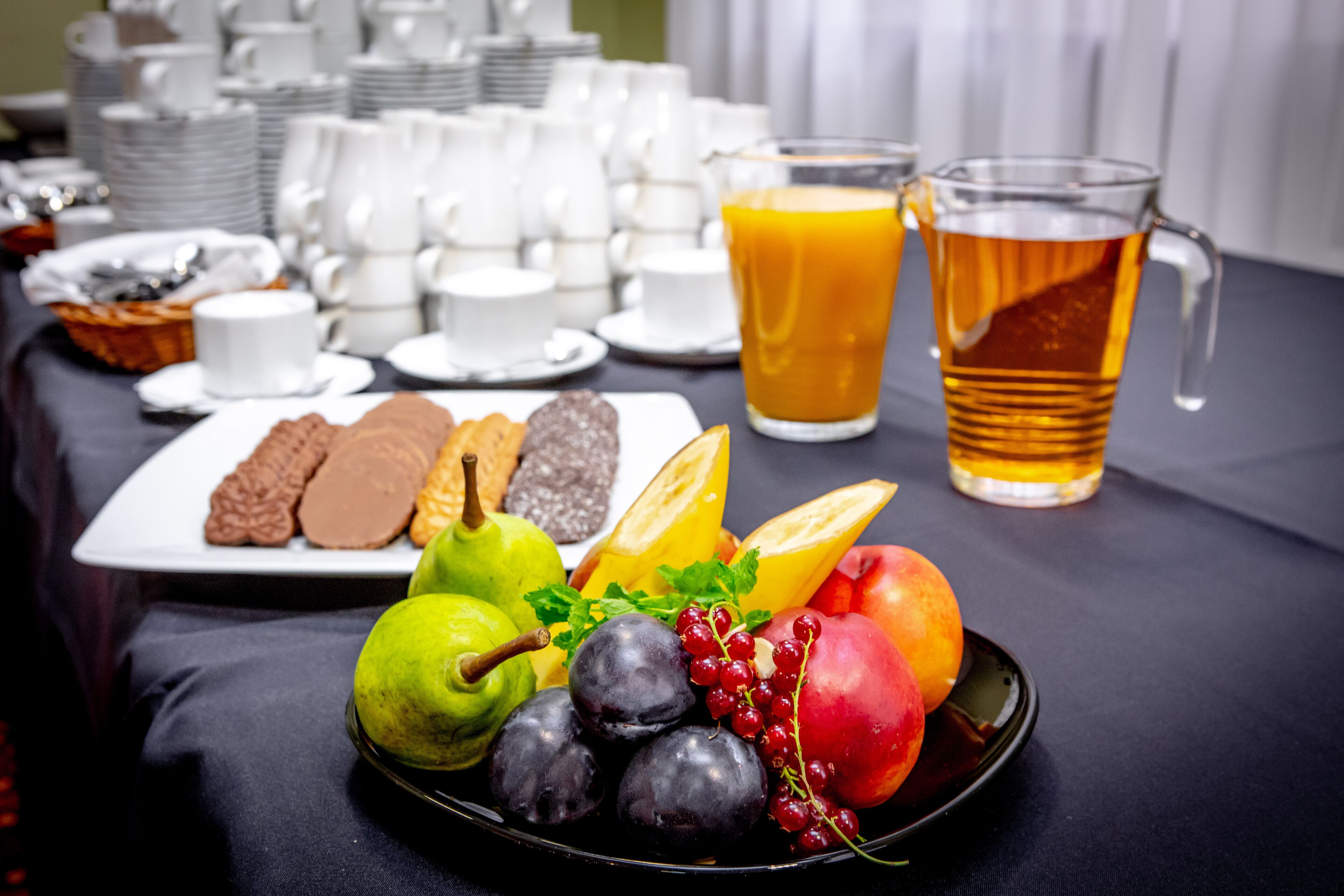 Ein Frühstücksbuffet mit Tellern voller Gebäck, Früchten und einem Krug Orangensaft.