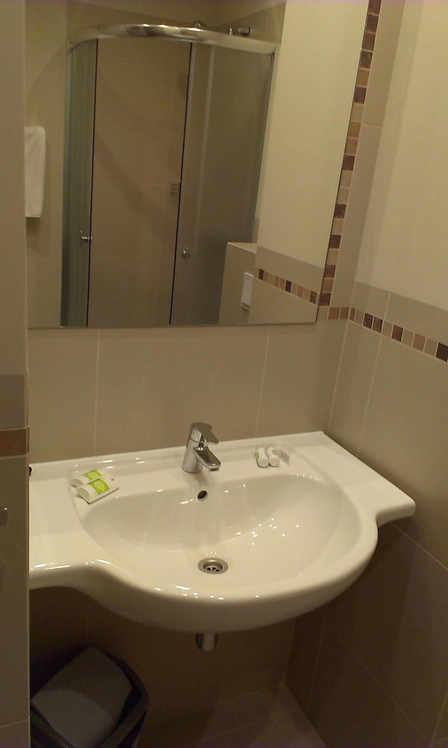 A bathroom with a white sink, a mirror, and a shower enclosure.
