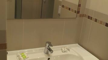 A bathroom with a white sink, a mirror, and a shower enclosure.