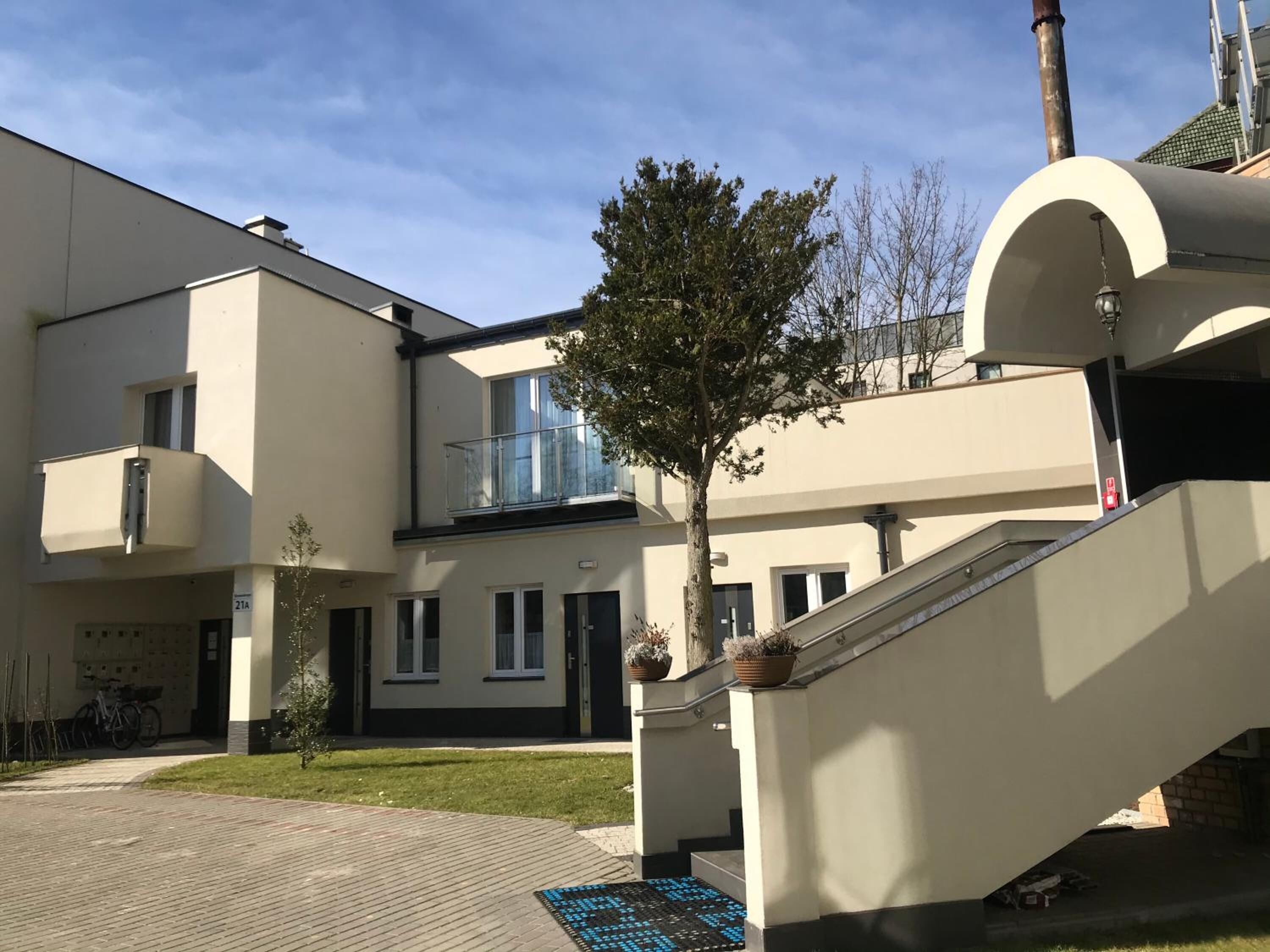 A modern building with a staircase, a tree, and a paved area.