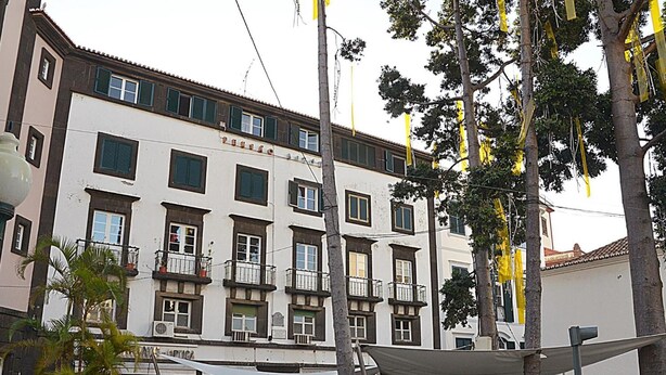 Um edifício de vários andares com varandas e um café no andar térreo.