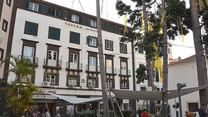 Um edifício de vários andares com varandas e uma loja no térreo.