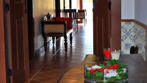 Un corridoio con porte in legno, una panca e un tavolo con candele e un vaso di vetro.