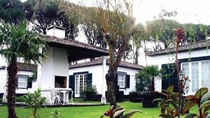Un edificio bianco con tetto in tegole, immerso nel verde e con palme.