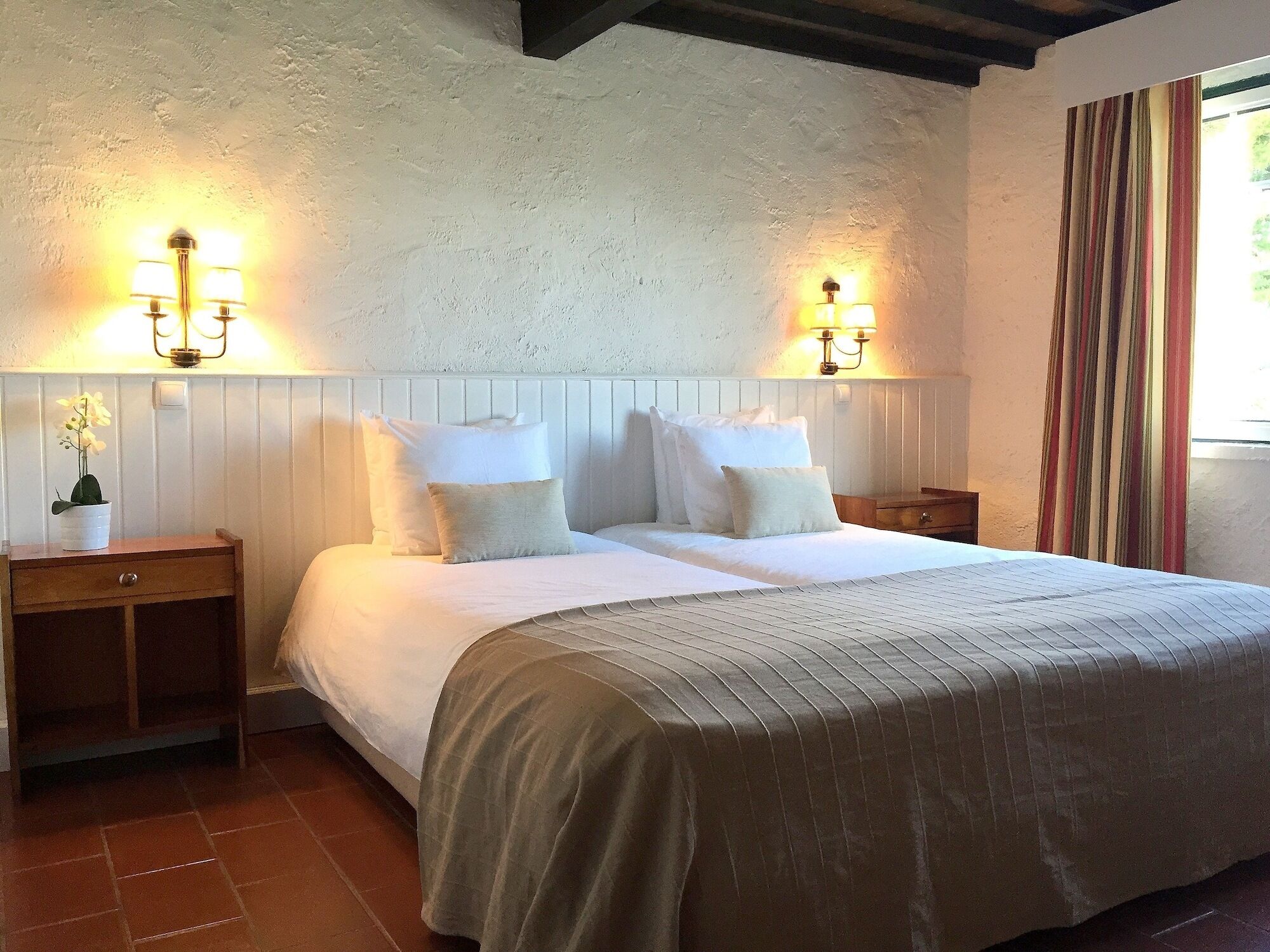A double bed with white linens and two bedside lamps.