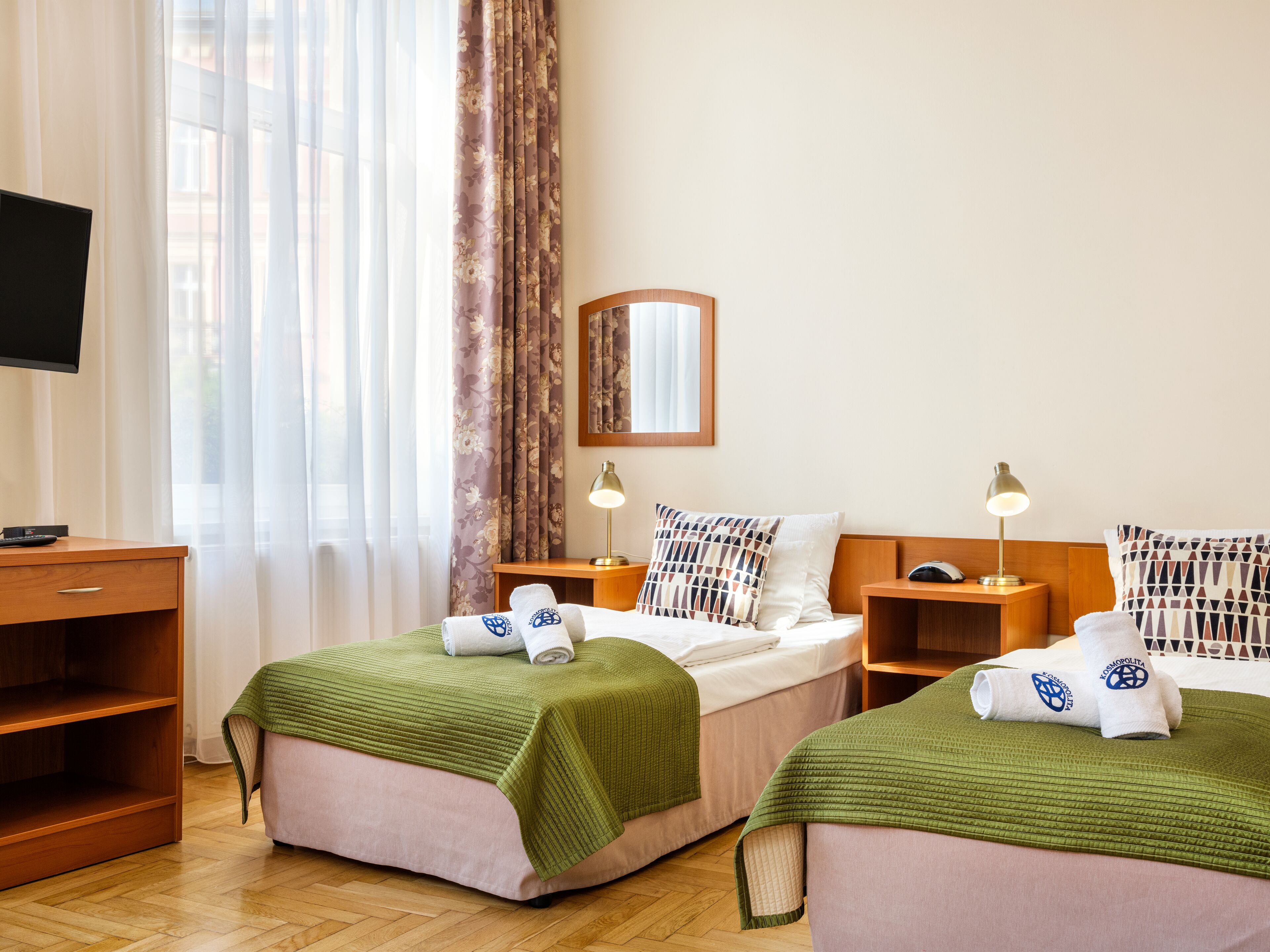 Une chambre d’hôtel avec deux lits, une télévision, un bureau et un miroir.