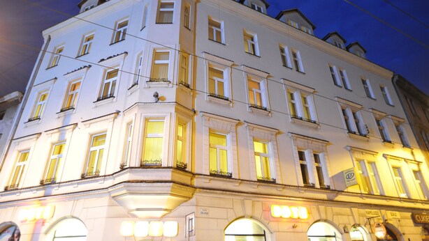 Un edificio de varios pisos con ventanas iluminadas y señalización.