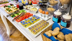 Un bufé con diversos alimentos, entre ellos sándwiches, frutas, quesos y salsas.