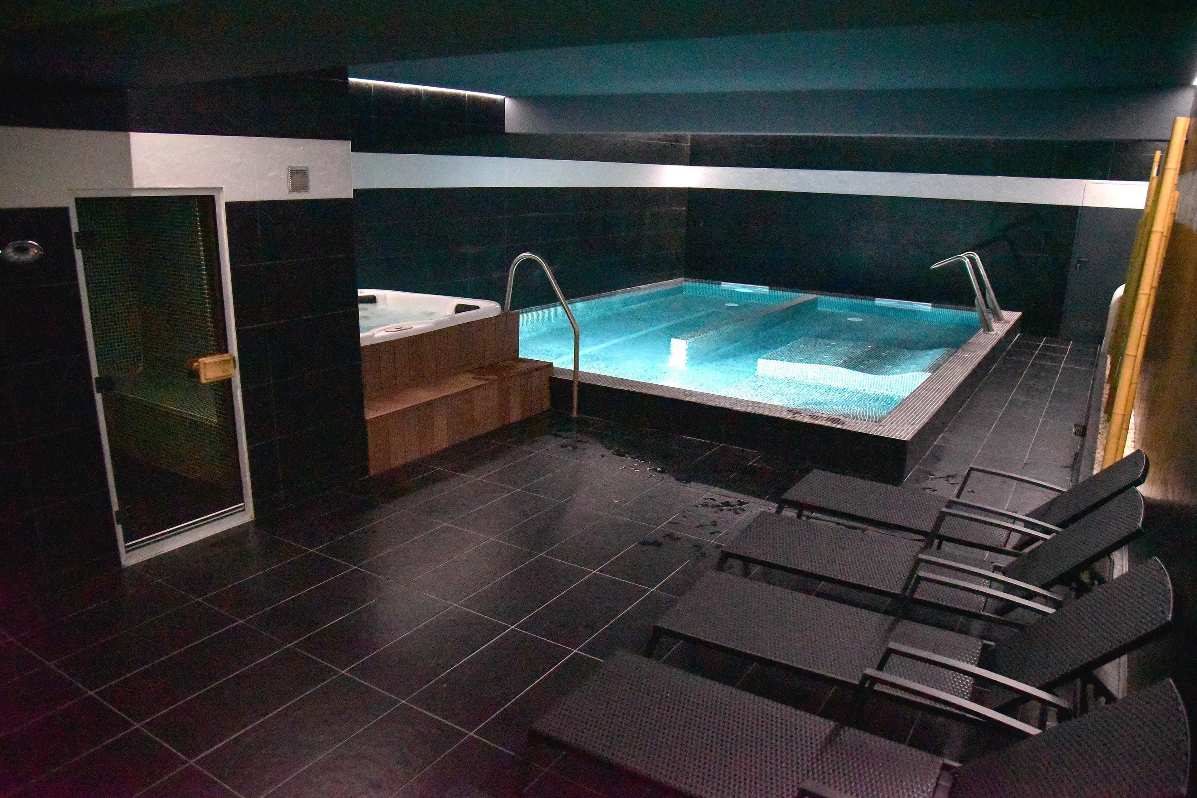 Ein moderner Poolbereich mit Whirlpool, Sitzgelegenheit und einer durchsichtigen Duschkabine.