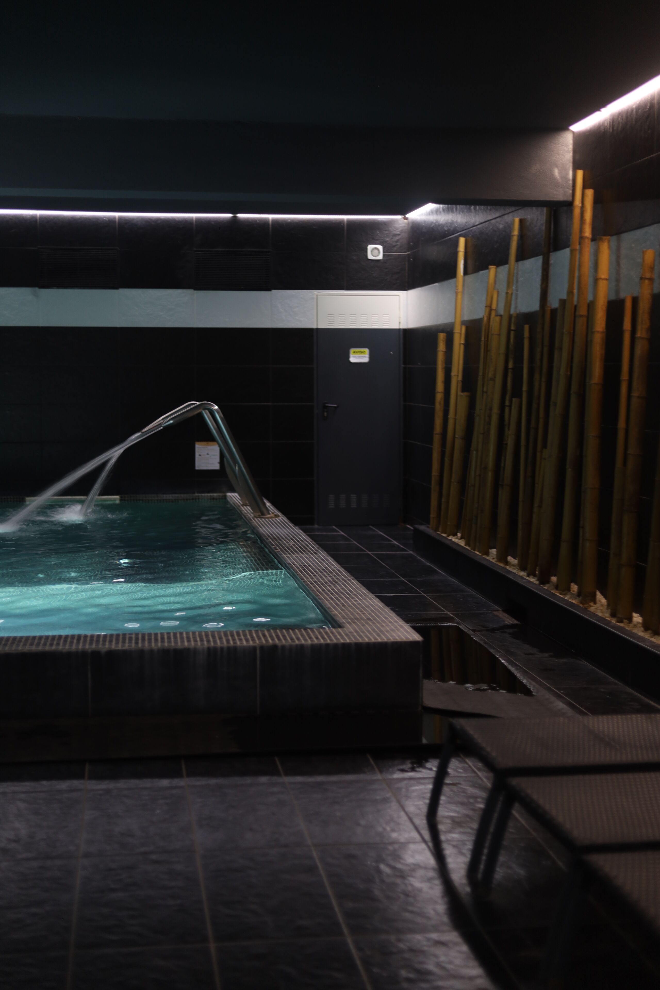Uma área de spa com hidromassagem, espaço para sentar e decoração em bambu.