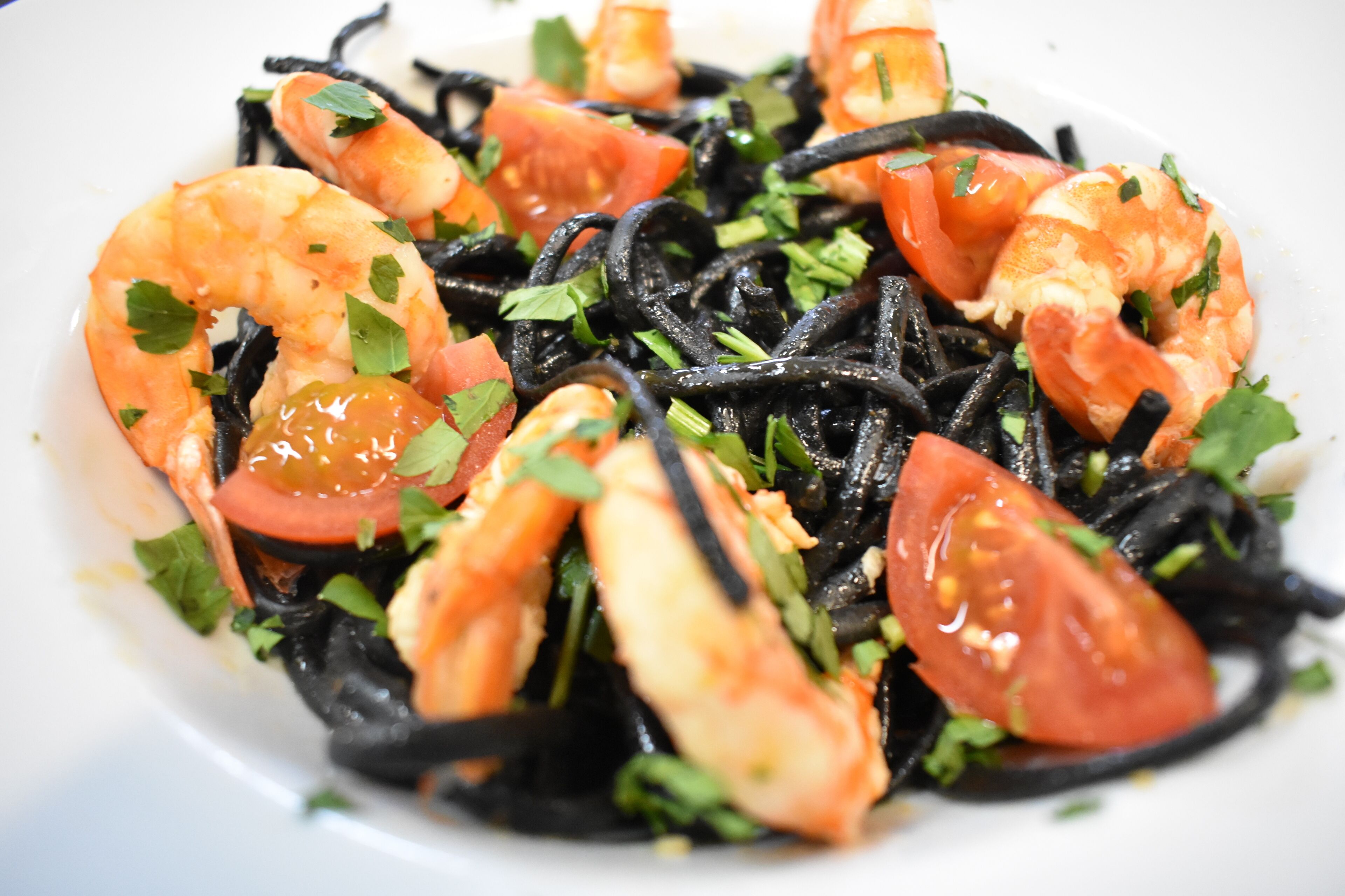 A plate of pasta with shrimp, tomatoes, and parsley.