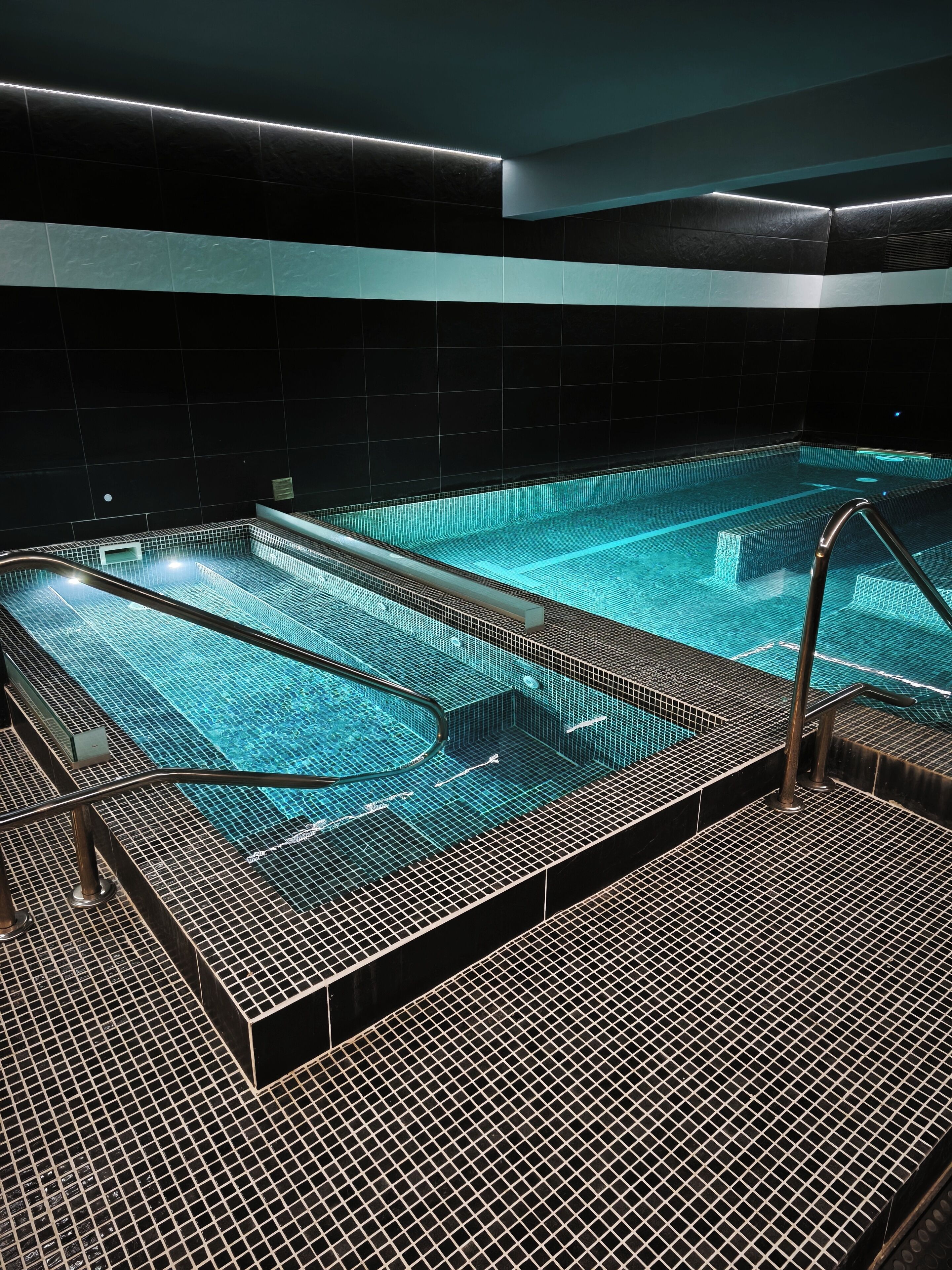Una piscina con piso de rejilla metálica y escalones para entrar al agua.