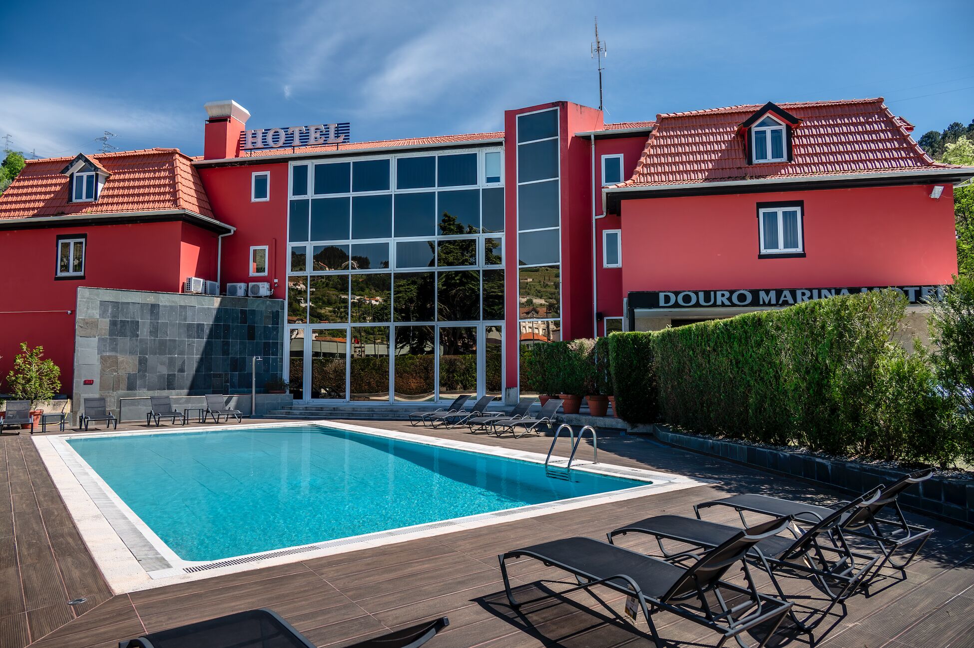 Un hotel con piscina, sillas de descanso y vistas del paisaje circundante.