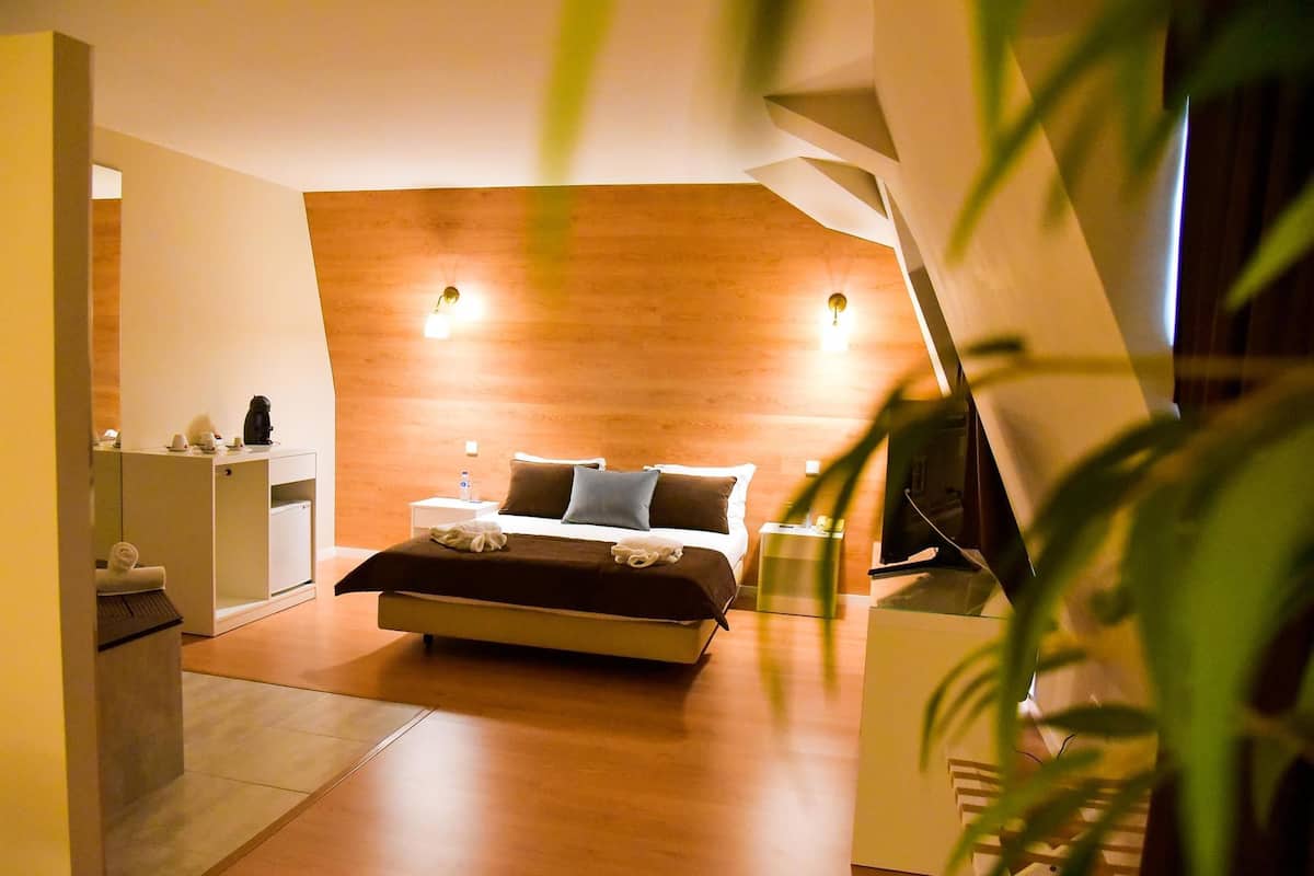 A modern bedroom with a wooden headboard, a bed with pillows, bedside tables, and a nightstand.