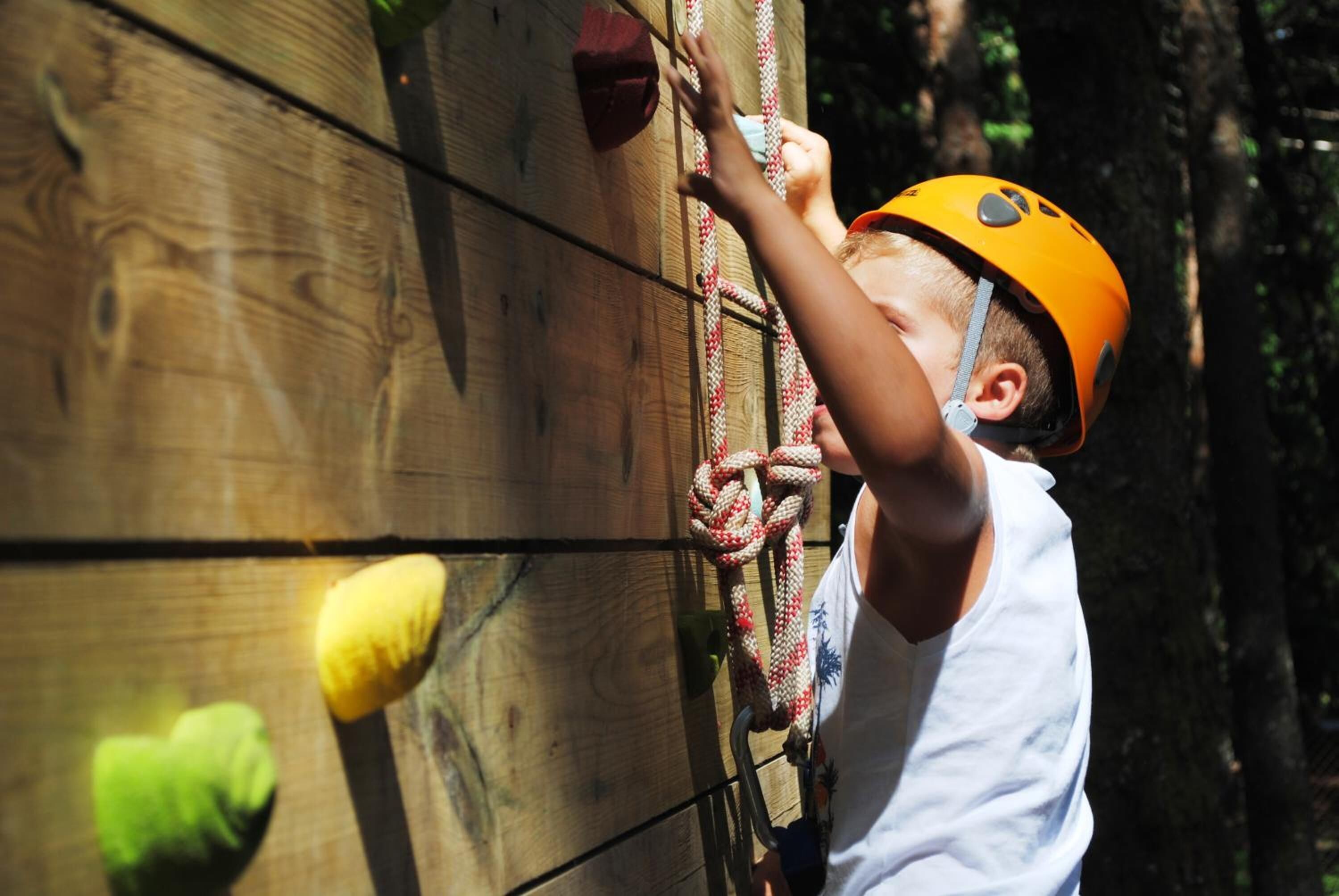 Una persona escalando una pared de madera con agarres para escalada.