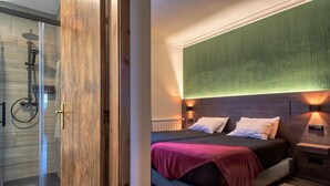 Un dormitorio moderno con cama, mesitas de noche y zona de ducha.