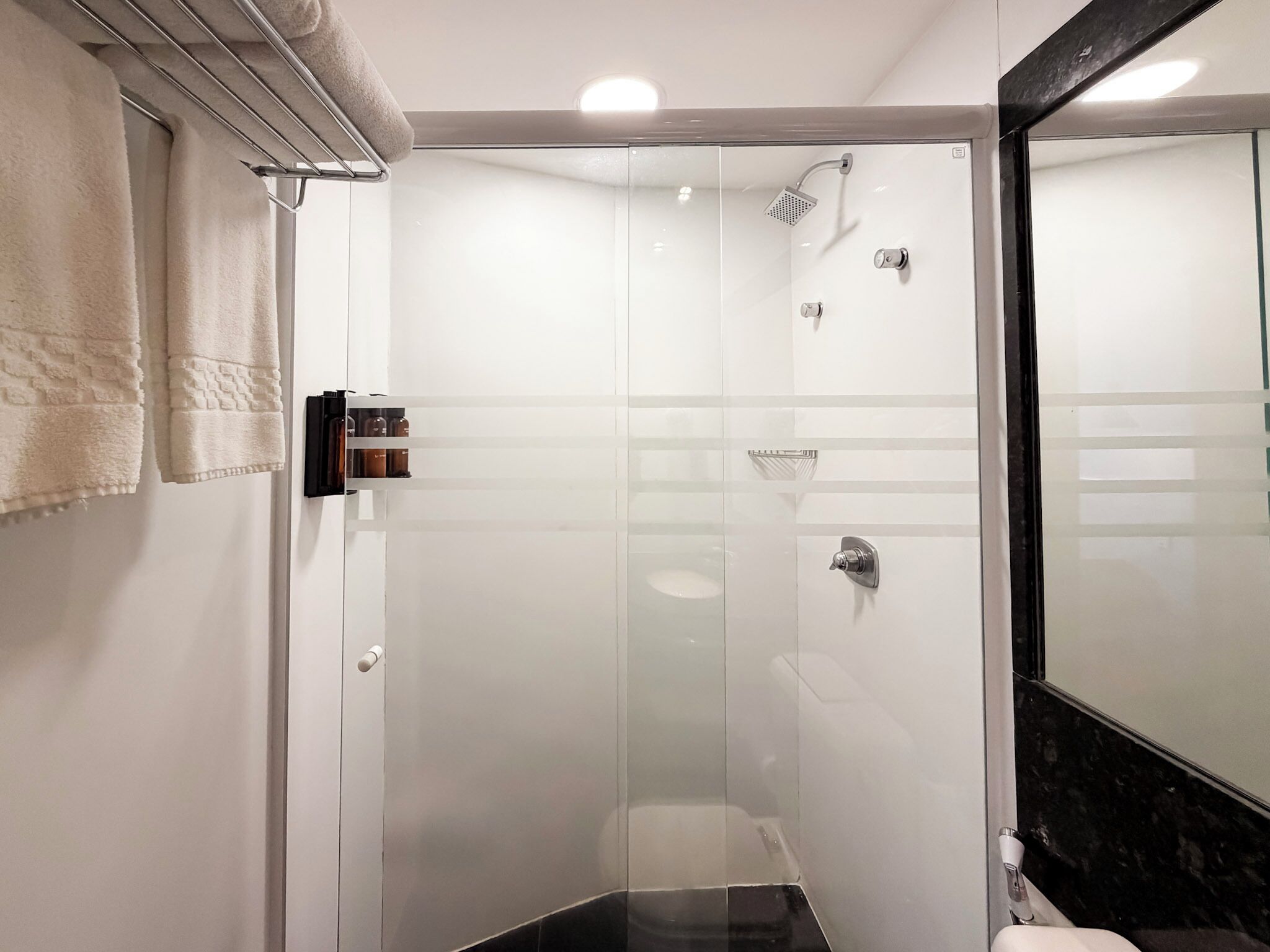 Un baño moderno con cabina de ducha de vidrio, un lavabo blanco y un espejo grande.