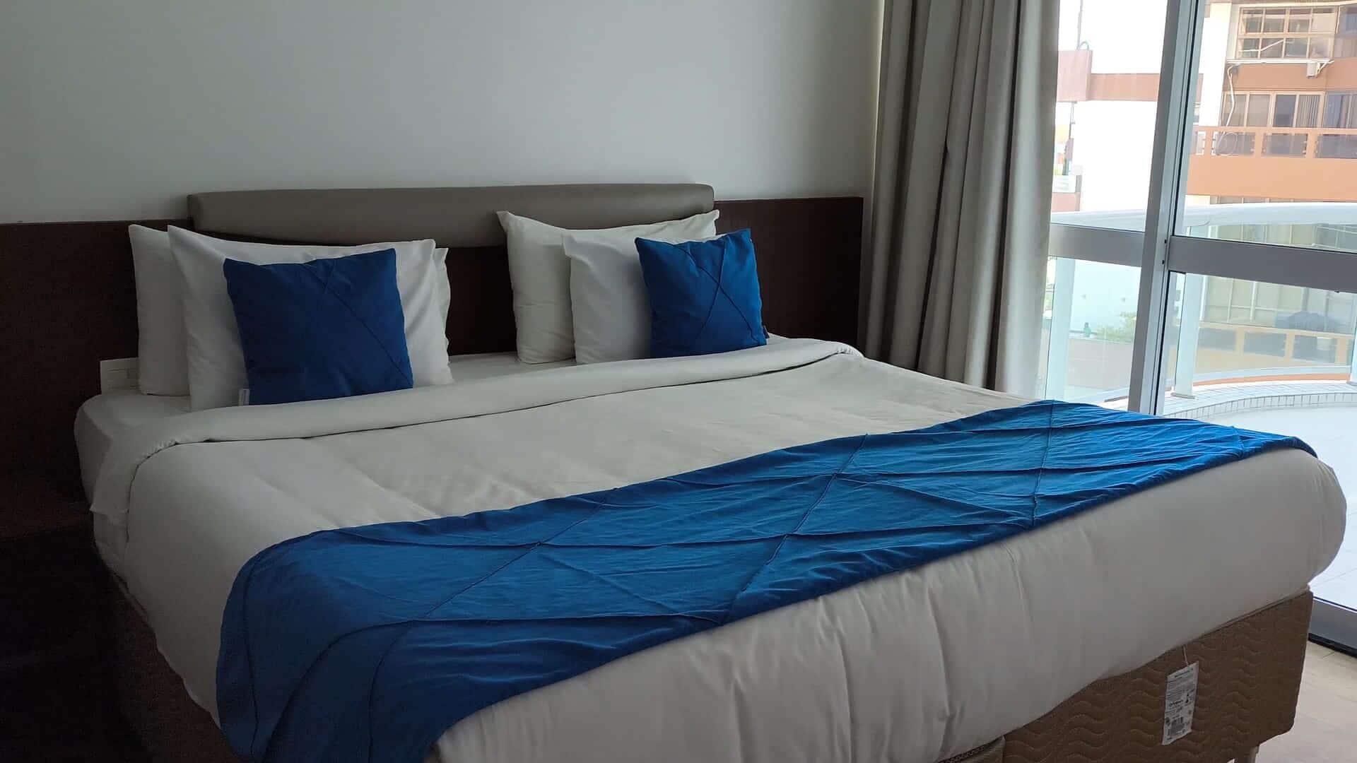 Habitación de hotel con una cama grande, cabecera y vistas por la ventana.