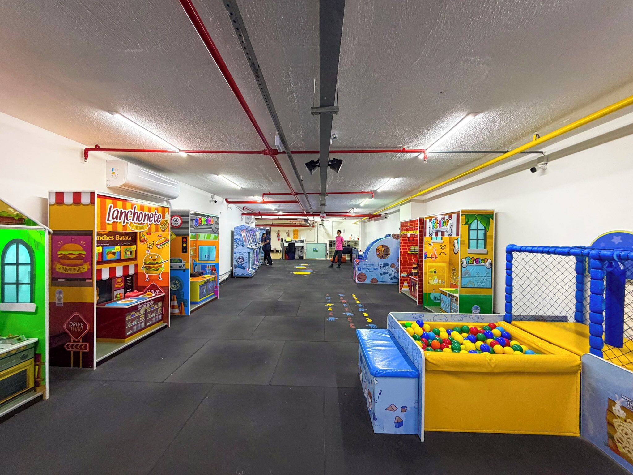 Un área de juego interior bien iluminada con diversas estaciones de juego, incluyendo una piscina de pelotas y una zona de juego tipo autolavado.