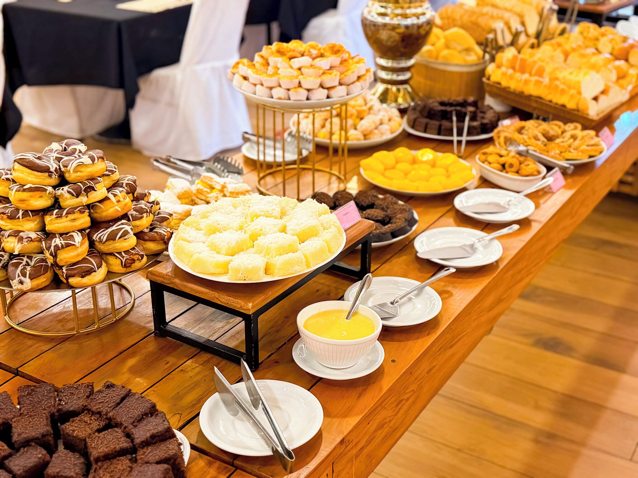 Una mesa de buffet con diversos alimentos, entre ellos, donuts, pasteles y postres.