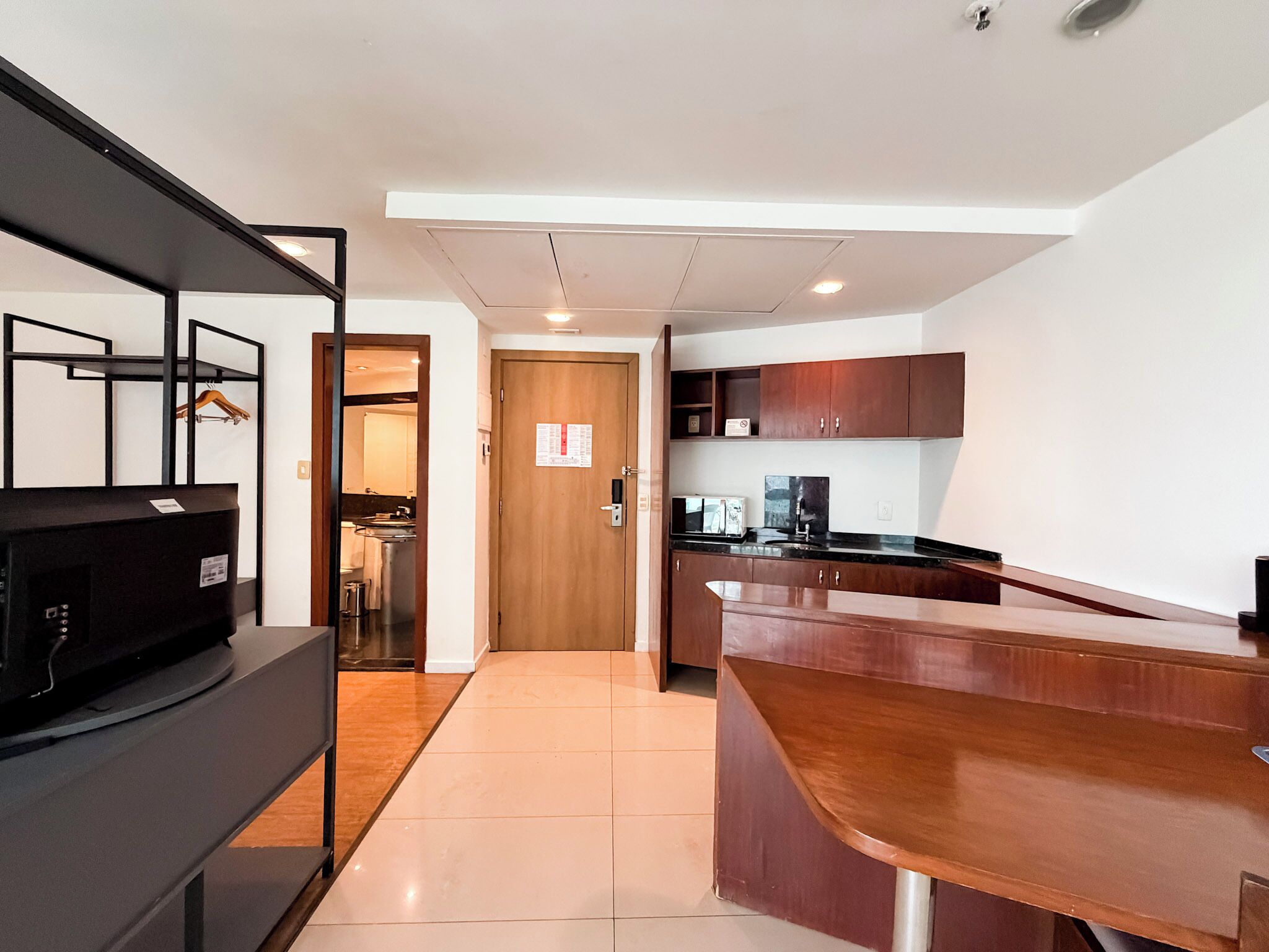 A modern kitchen with wooden cabinets, a black countertop, and a wooden door.