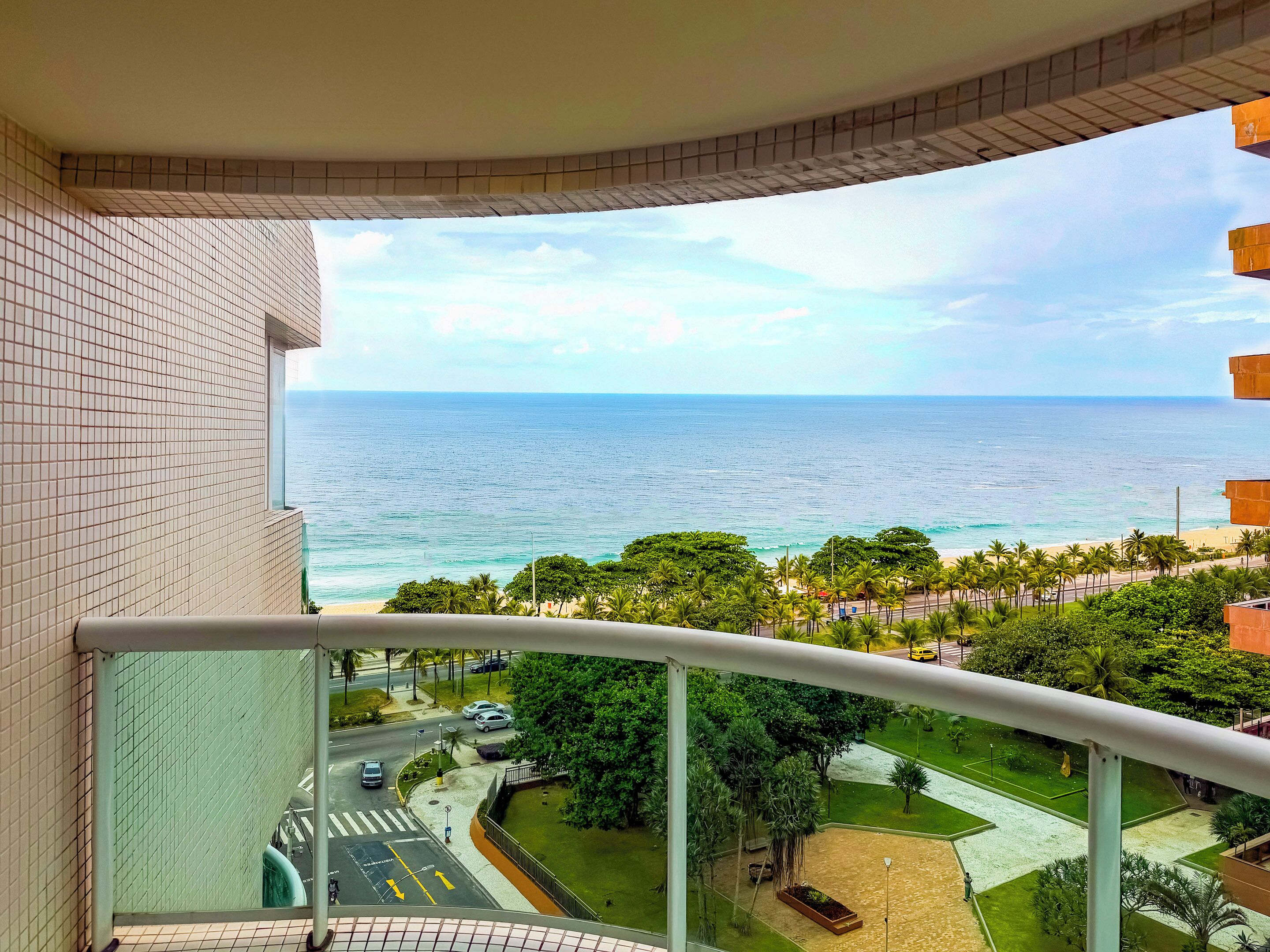 A balcony with a view of the ocean and a road with cars.