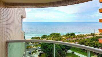 A balcony with a view of the ocean and a road with cars.
