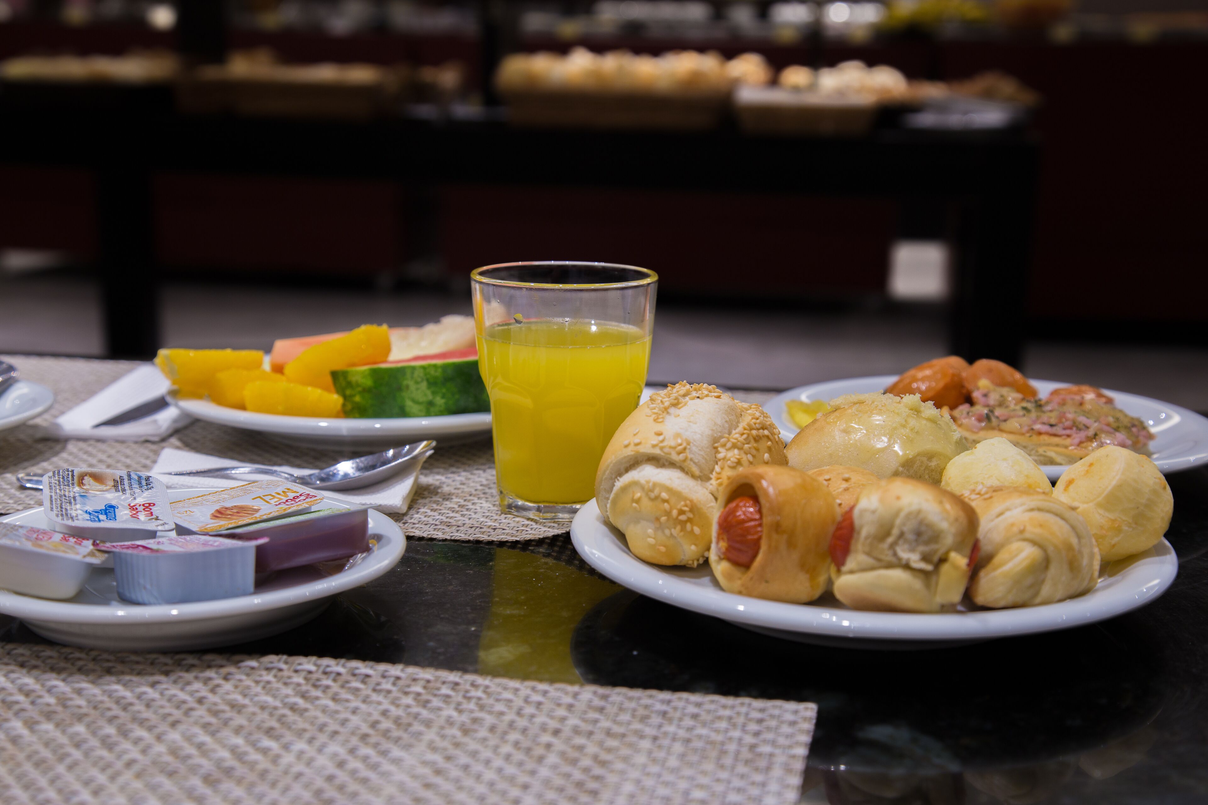 Un bufé de desayuno con diferentes alimentos y un vaso de jugo de naranja.