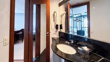 Une salle de bain moderne avec un grand miroir, un lavabo et des sèche-cheveux fixés au mur.