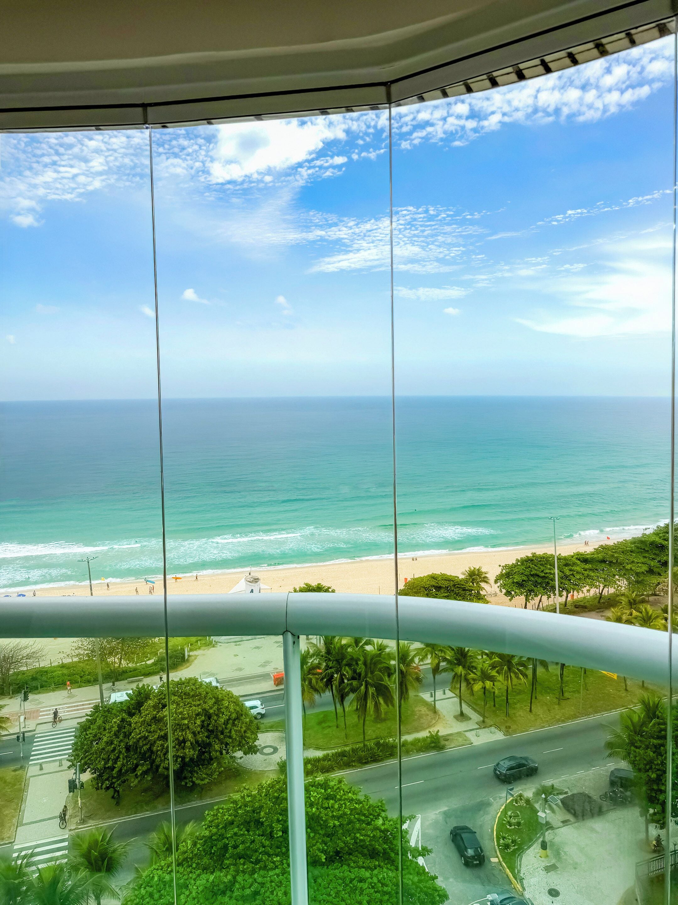 Une vue depuis un balcon donnant sur une plage, avec un ciel dégagé.