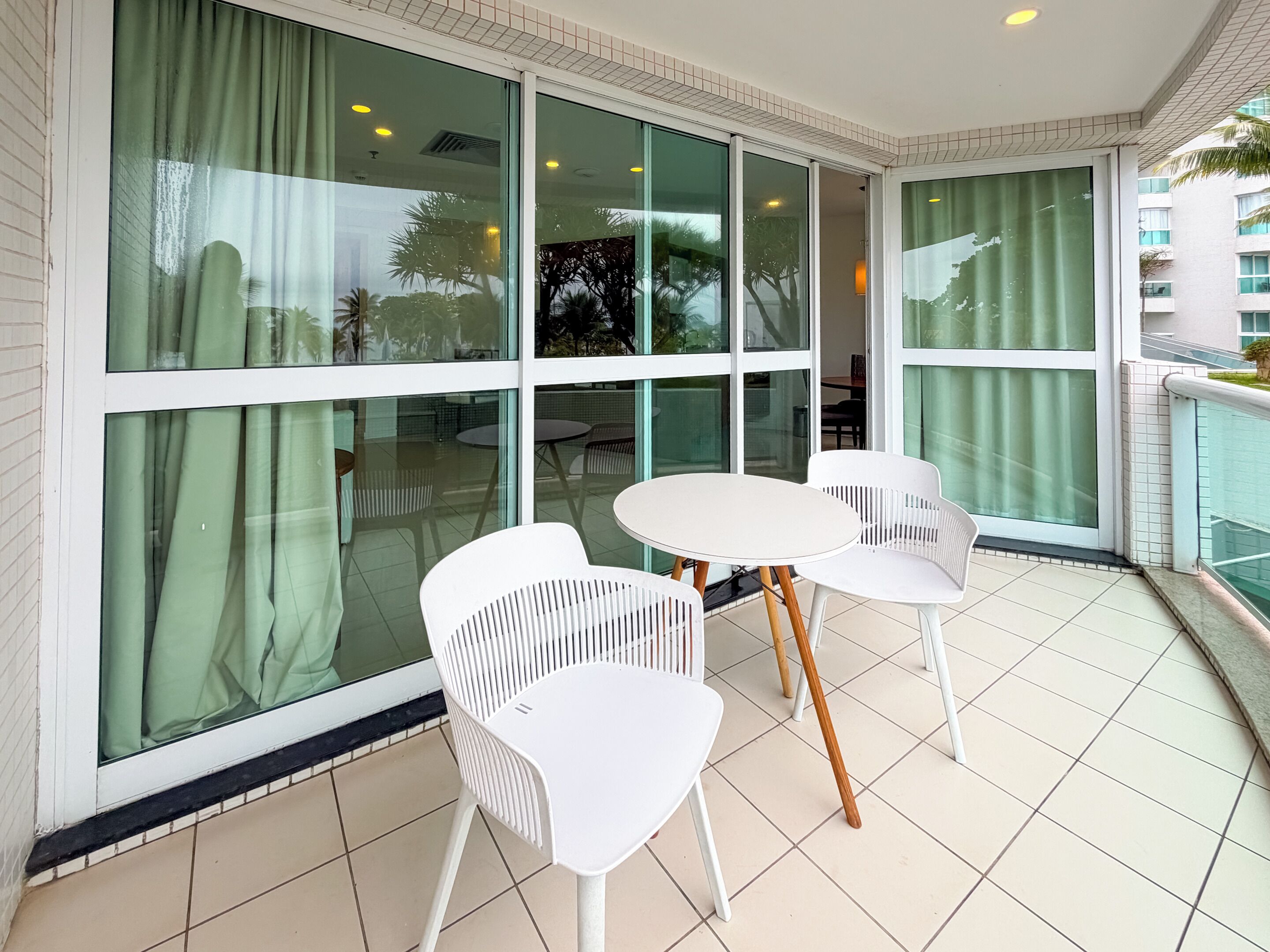 A balcony with a table and chairs, large windows, and a view of the outside.