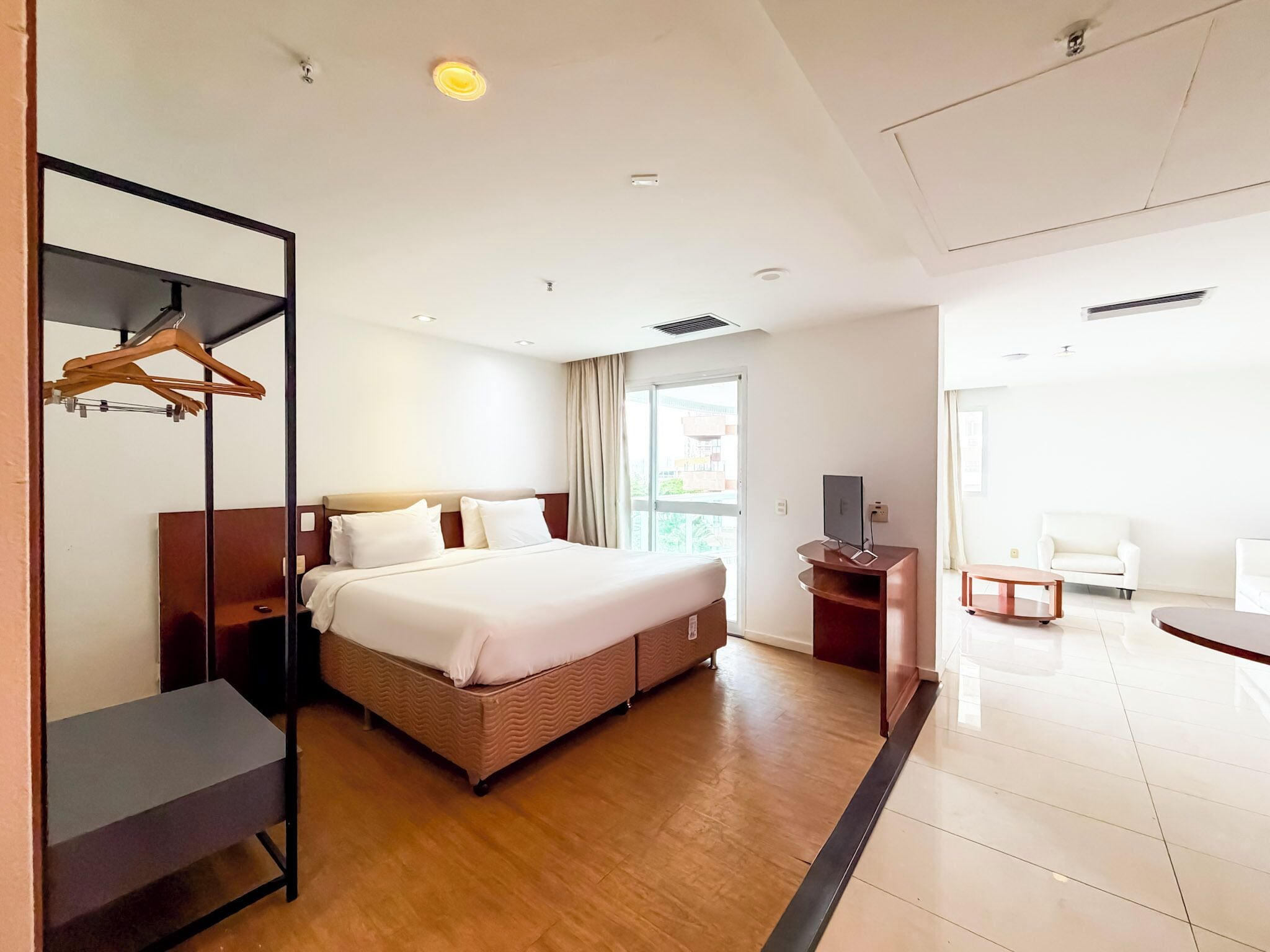 A hotel room with a bed, a desk, a chair, and a wardrobe.