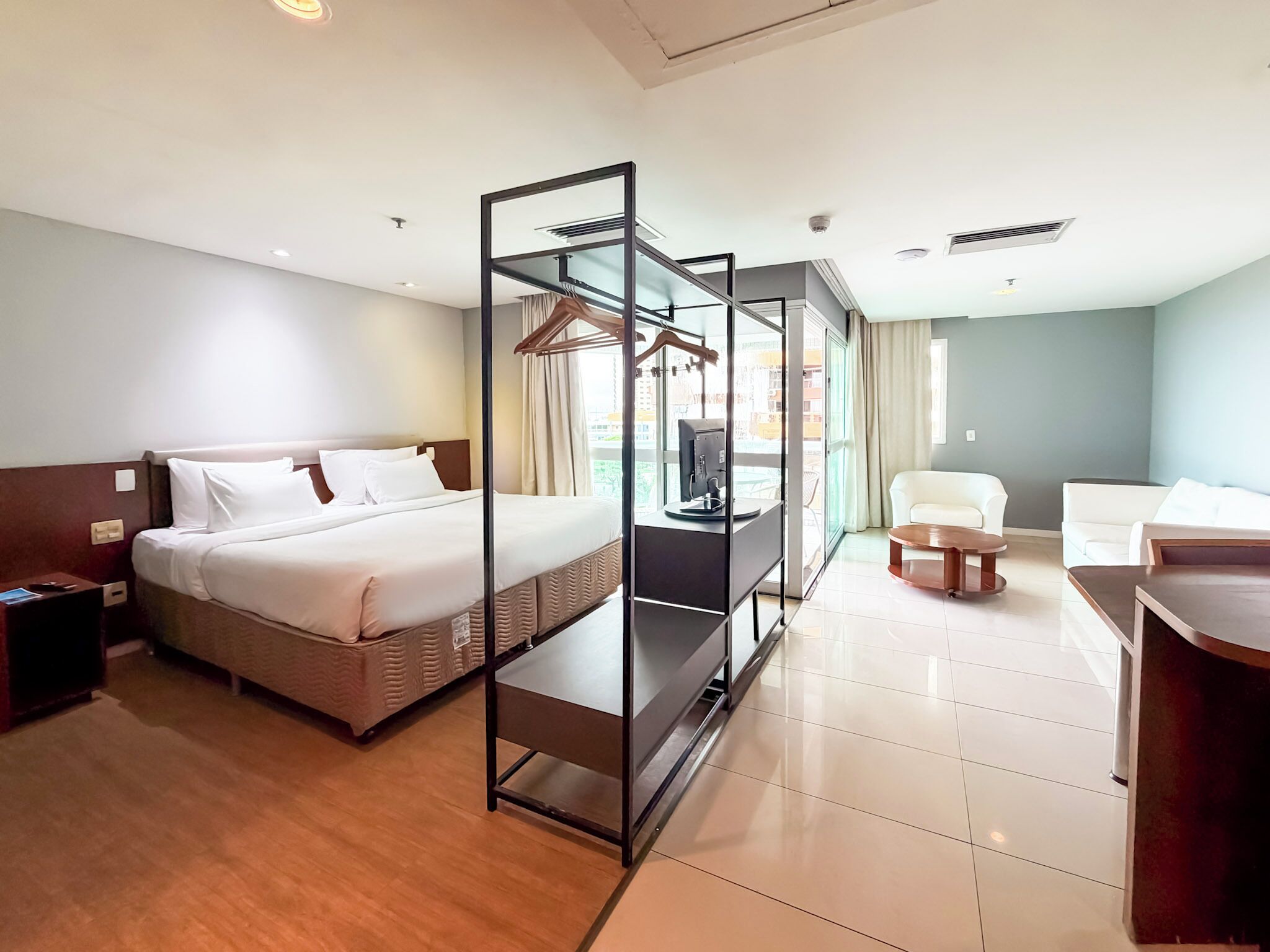 A hotel room with a bed, a seating area with a chair and a table, and a TV.
