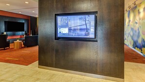 Un vestíbulo moderno con una gran pantalla digital, asientos cómodos y una pared decorativa.