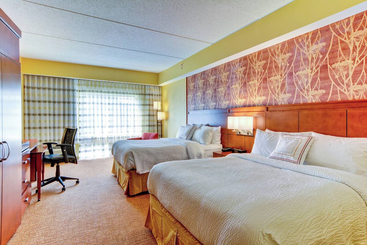 Una habitación de hotel con dos camas, un escritorio y una silla.