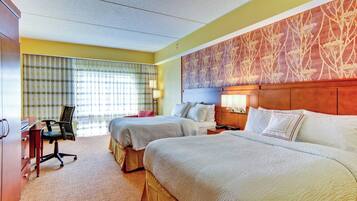 A hotel room with two beds, a desk, and a chair.