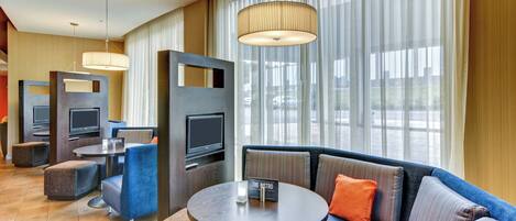 Une chambre d’hôtel moderne avec un canapé, un pouf et une table ronde sur laquelle est posé un panneau.