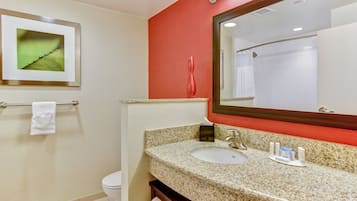 Un baño con lavabo de granito, espejo, toallero y un cuadro enmarcado en la pared.