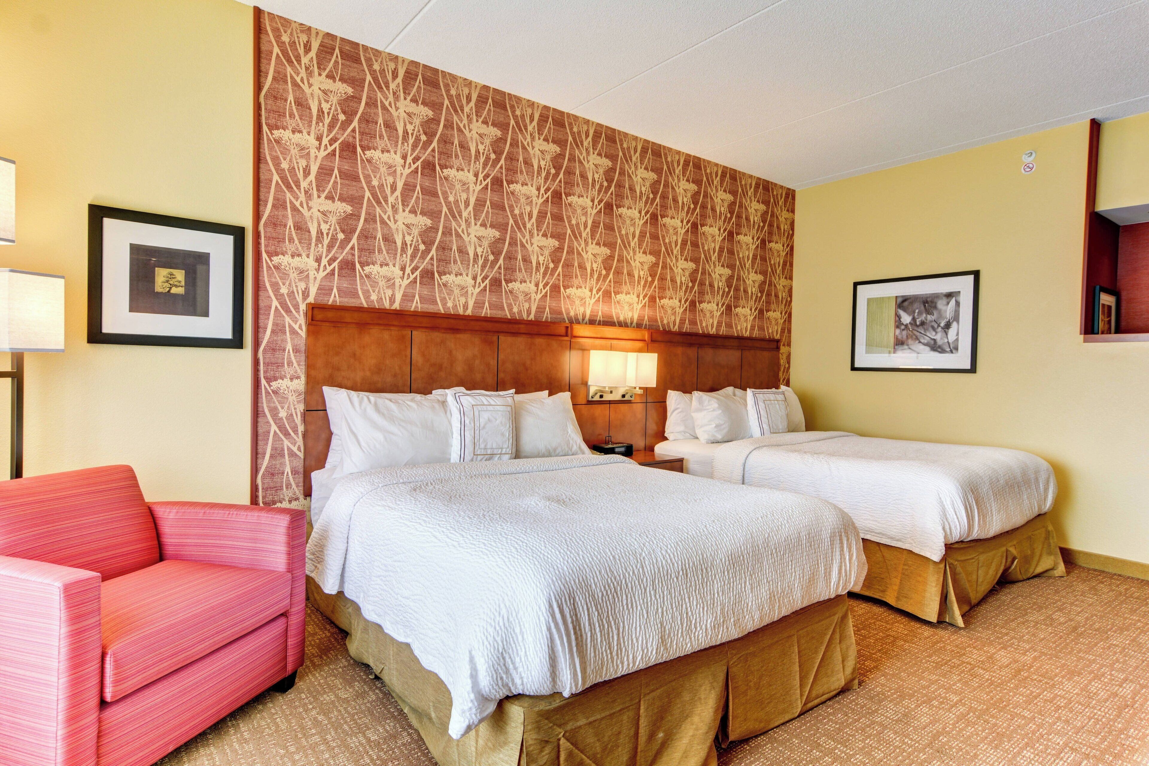 Ein Hotelzimmer mit zwei Betten, einem roten Sofa und einer Wand mit Muster.