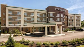 Un hotel Courtyard Marriott con una estructura de varios pisos, una entrada cubierta y un área de estacionamiento.