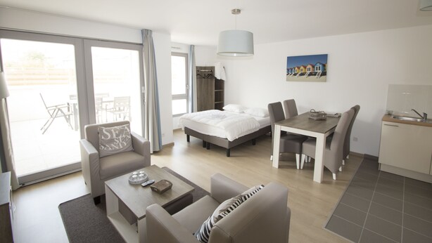 A modern hotel room with a bed, a dining table, a sofa, and a small kitchen area. - Evancy Bray-Dunes (Bray-Dunes)