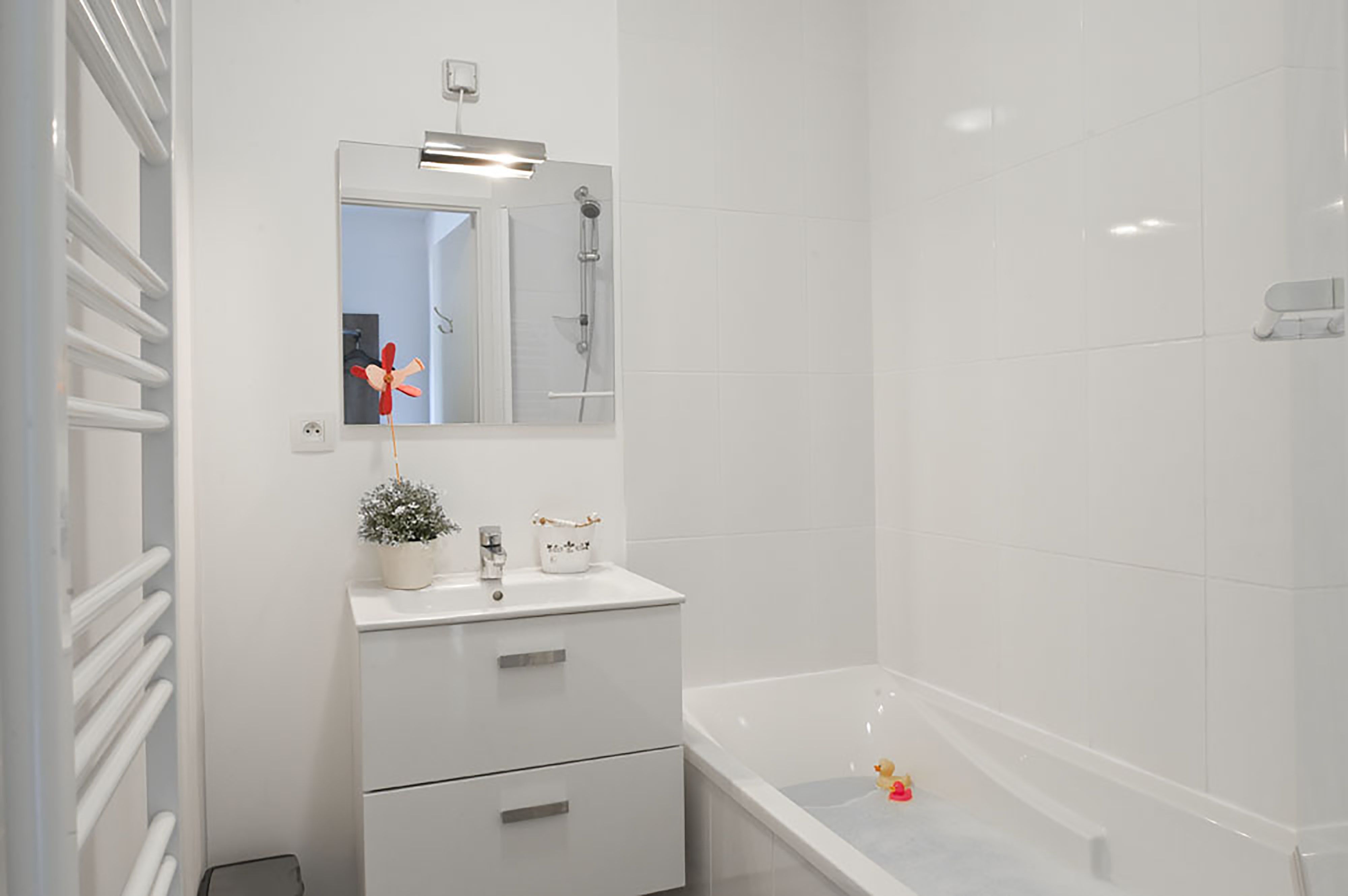 A modern bathroom with a white vanity, a large mirror, a shower, and a bathtub.