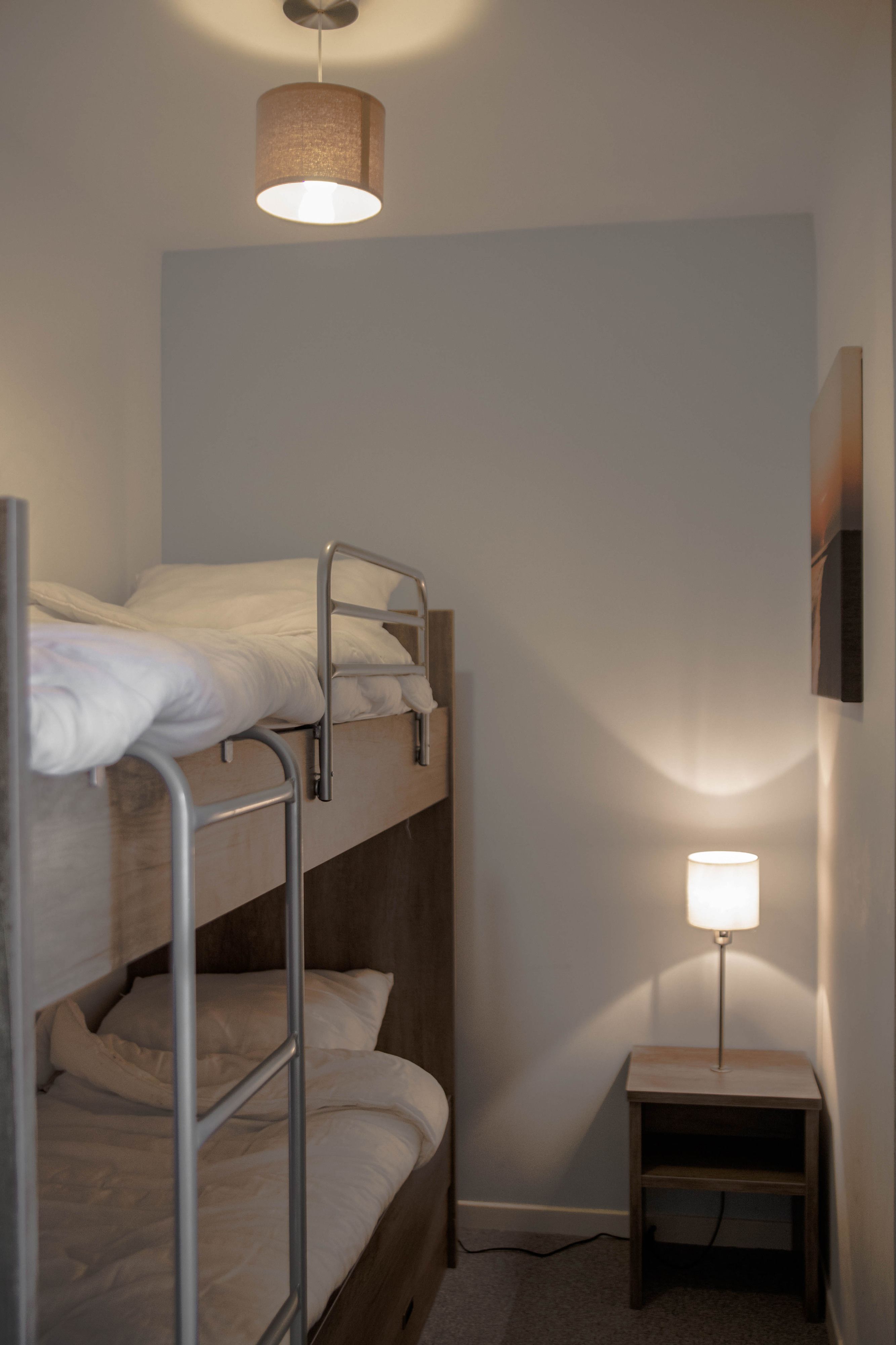 Ein Schlafraum mit Etagenbett, kleinem Nachttisch und Lampe.