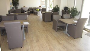 A conference room with tables and chairs, a projector, and potted plants. - Evancy Bray-Dunes (Bray-Dunes)