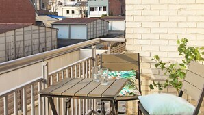 A balcony with a table and chairs, a view of neighboring buildings, and a brick wall. - Evancy Bray-Dunes (Bray-Dunes)