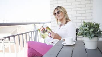 A person sitting at a table with a magazine, a cup, and a plant.