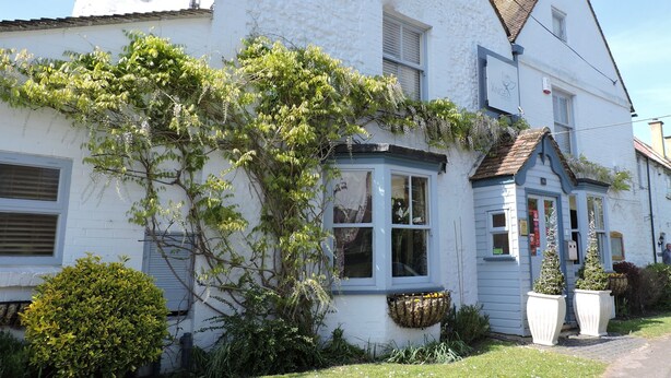 A white building with a blue window frame, a chimney, and a small porch area. - The Angel B&B (Aylesbury)